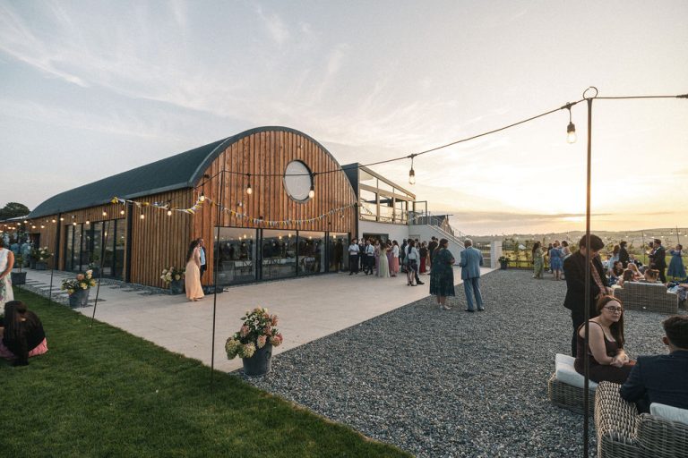 Wedding Guests enjoying the outside space of The Anglesey Barn during a beautiful sunset